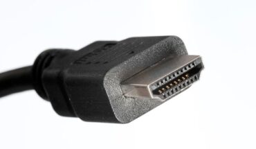 Lähikuva mustasta HDMI-kaapelin urosliittimestä valkoisella taustalla