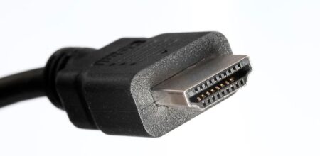 Lähikuva mustasta HDMI-kaapelin urosliittimestä valkoisella taustalla